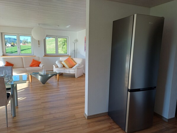 Ein modernes Wohnzimmer mit einer Couch, einem Couchtisch und einem großen Kühlschrank.