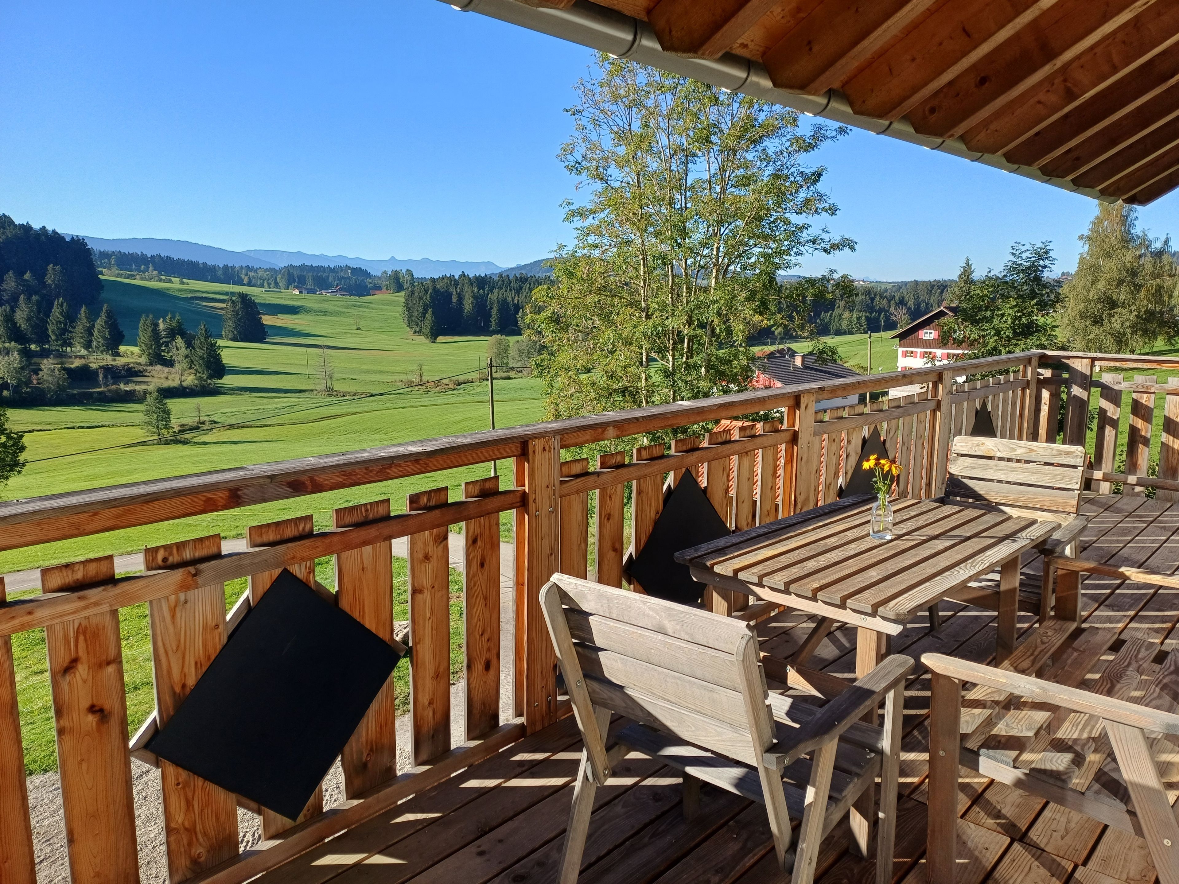 A wooden deck with outdoor seating and a view of a green landscape.