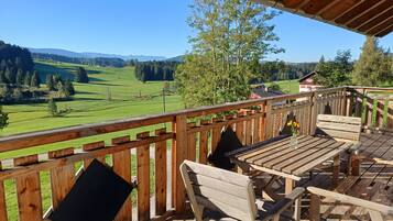 A wooden deck with outdoor seating and a view of a green landscape.