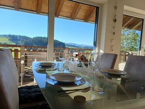 A dining table set with plates, glasses, and cutlery, overlooking a scenic landscape.