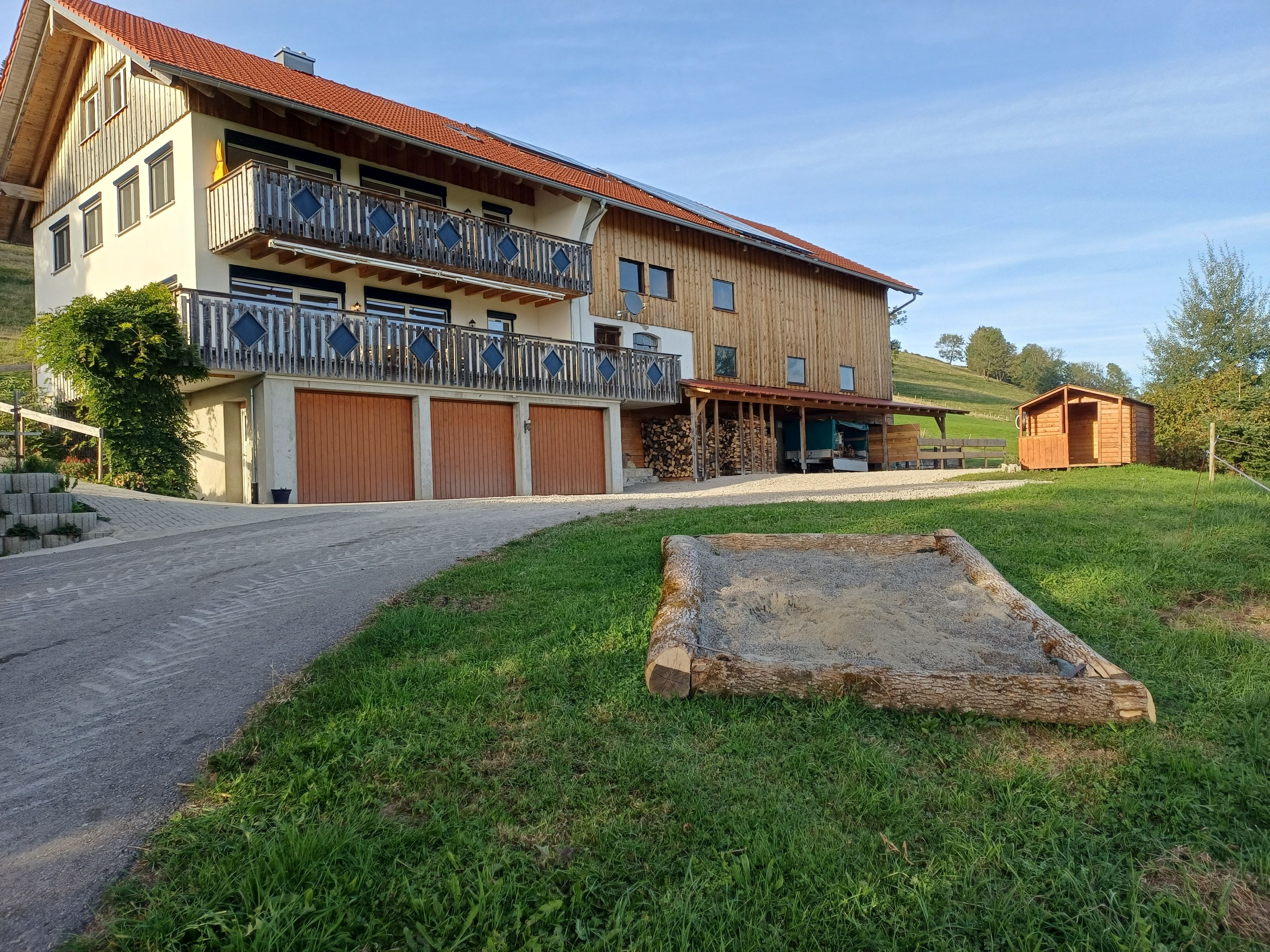 A two-story building with a balcony, a wooden deck, and a small shed.