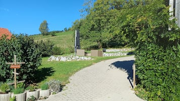 A paved pathway leading through a landscaped area with a stone wall and greenery.