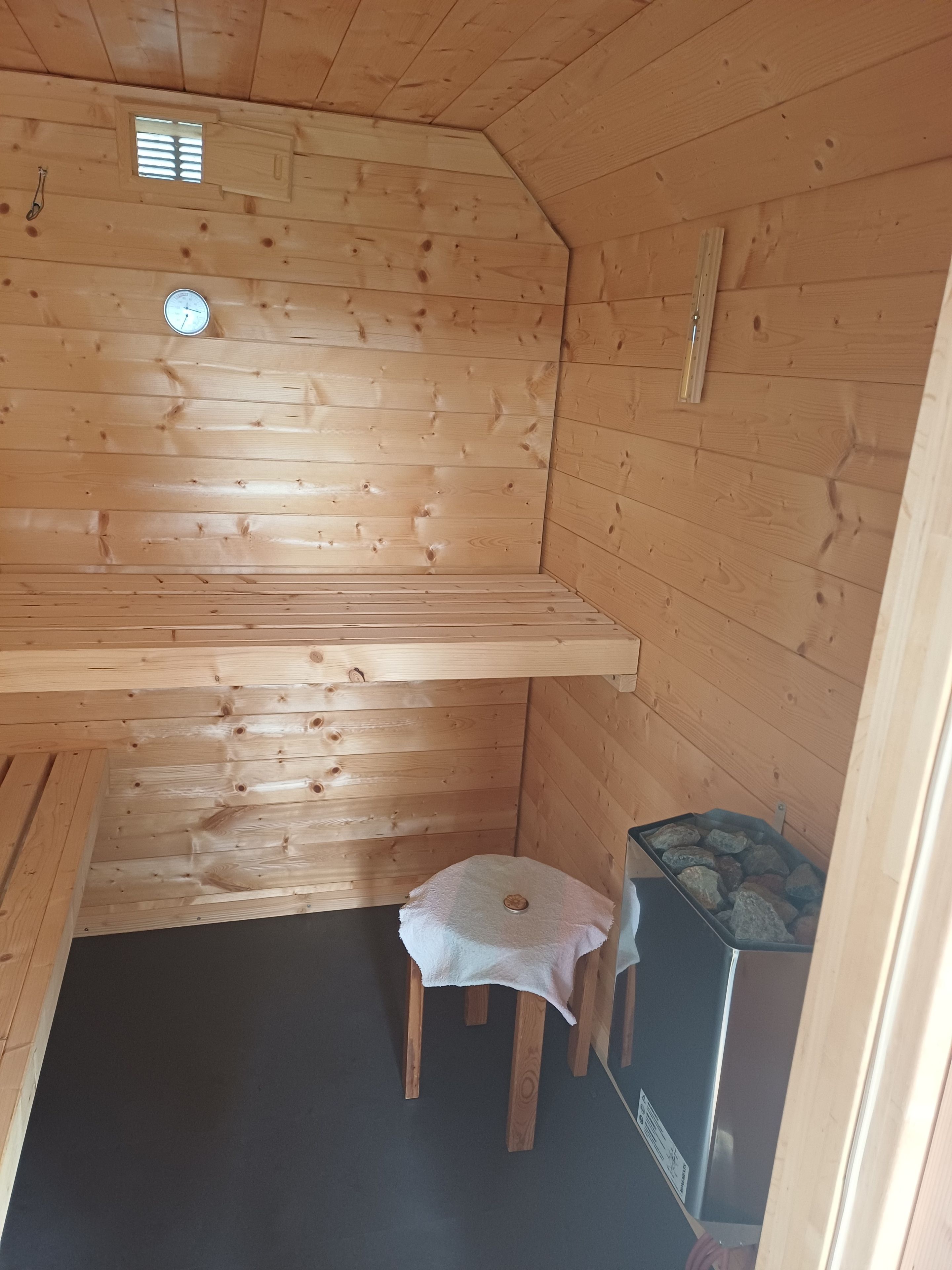 Ein Holzblockhaus-Interieur mit einer Bank, einem kleinen Tisch und einem Heizgerät.