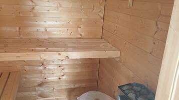 Ein Holzblockhaus-Interieur mit einer Bank, einem kleinen Tisch und einem Heizgerät.