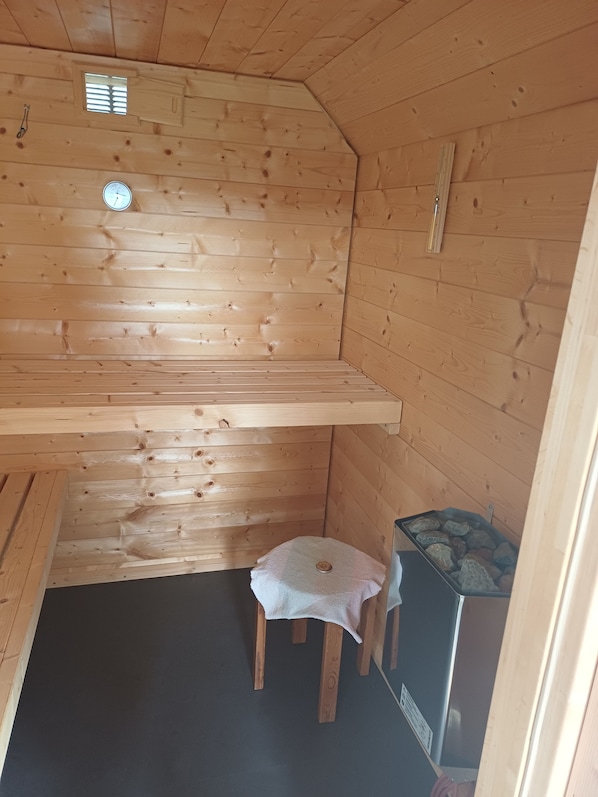 A wooden cabin interior with a bench, a small table, and a heater.