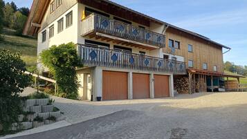 Ein zweistöckiges Gebäude mit Balkon, Garage und überdachter Veranda.