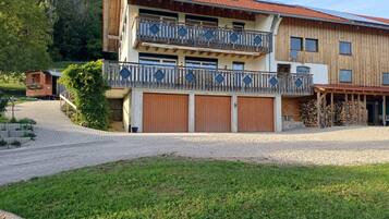 Ein zweistöckiges Gebäude mit Balkon, überdachter Auffahrt und Holzstapel.