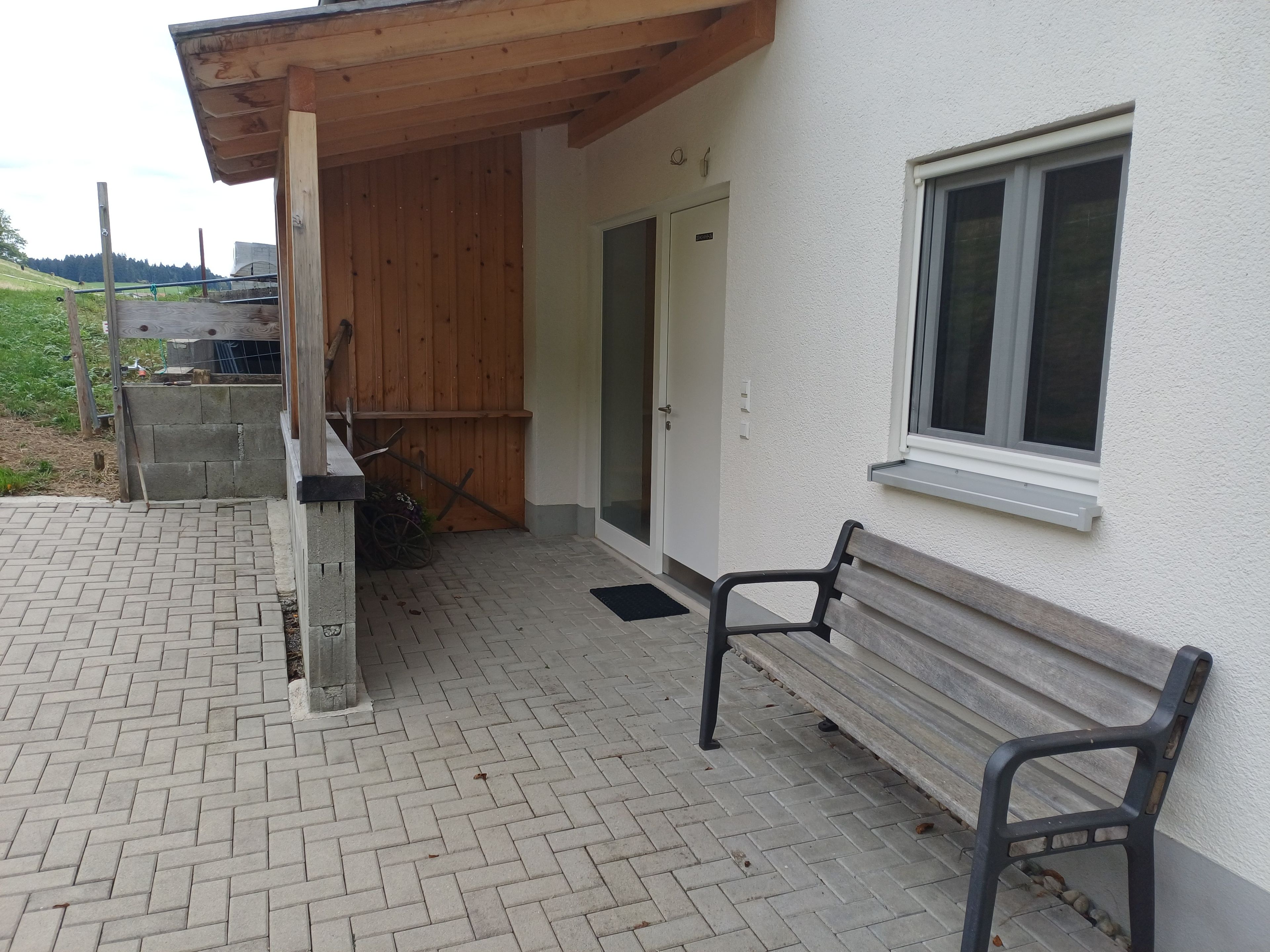 Ein Gebäude mit einer Holzveranda, einer Bank und einem Fenster.