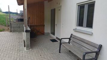 Ein Gebäude mit einer Holzveranda, einer Bank und einem Fenster.