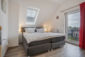 Ein Schlafzimmer mit einem Bett, Nachttischen, einem Fenster und Blick ins Freie.