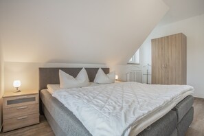 Un dormitorio con cama, mesitas de noche, lámpara y armario.