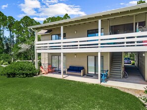 A two-story building with a covered patio area, outdoor seating, and a staircase leading to an upper level. - Seascape Villa 95E *Newly updated and quiet villa with beach access* (Miramar Beach)