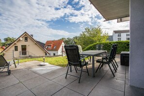 Eine Terrasse im Freien mit Tisch und Stühlen, einem Hydranten und Blick auf benachbarte Häuser.