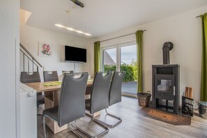 Eine moderne Küche mit Essbereich, inklusive Tisch und Stühlen, einem Fernseher und einem Kaminofen.