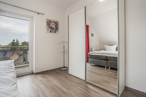 Ein Schlafzimmer mit einem Bett, einem Spiegel, einem Heizkörper und einem Fenster.