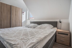 Un dormitorio con cama, mesitas de noche y ventana.