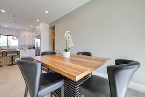 Eine moderne Küche mit weißen Schränken, einem Holztisch und schwarzen Stühlen.