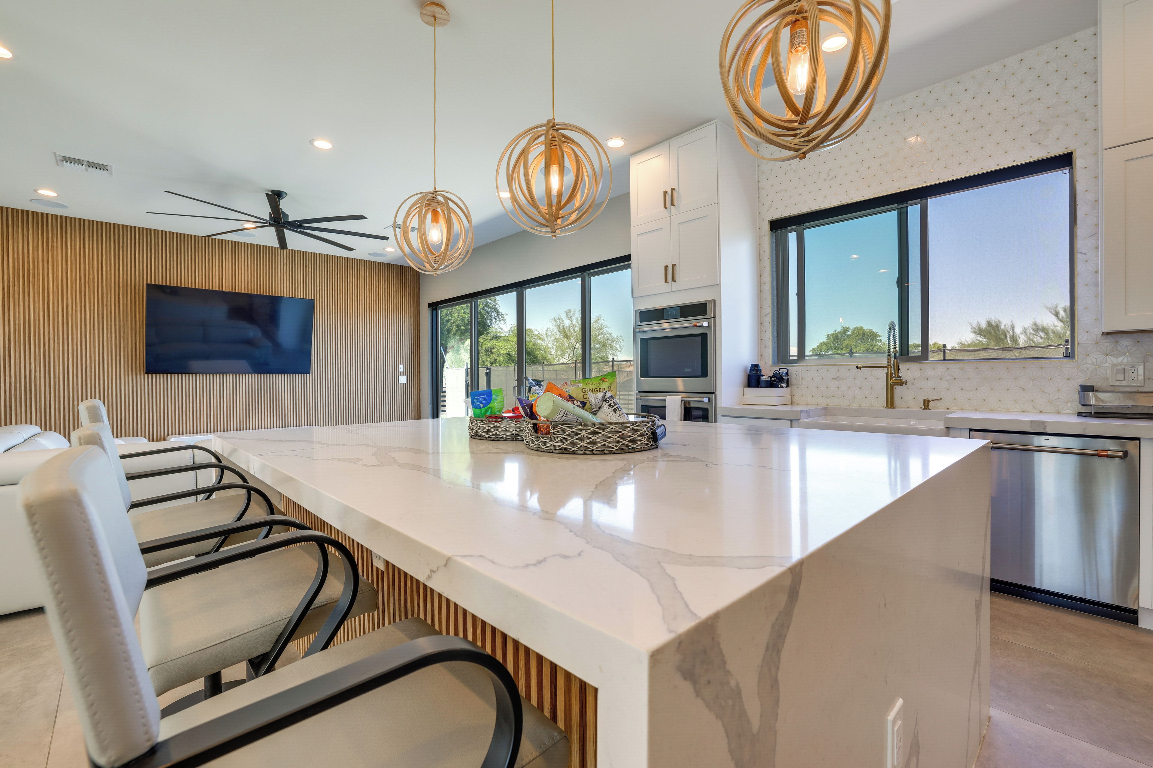 A modern kitchen with a large island, built-in appliances, and a dining area with chairs.