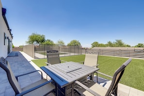 An outdoor patio with a table and chairs, a pool, and a view of a fenced area with trees. - 1 Mi to South Mtn Park! Home w/ Poolside Oasis (Phoenix)