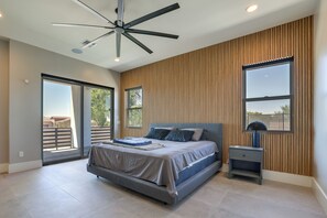 A modern bedroom with a large bed, a ceiling fan, and a view of the outdoors through a sliding door. - 1 Mi to South Mtn Park! Home w/ Poolside Oasis (Phoenix)