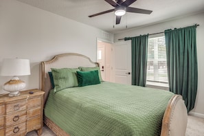 A bedroom with a bed, a nightstand, a lamp, a ceiling fan, and a window with curtains. - City Skyline Views! Modern Dtwn Jax Townhome (Jacksonville)