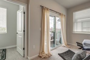 Ein Zimmer mit einer Schiebetür aus Glas, einer weißen Tür, einem Fenster mit Jalousien und einem kleinen Teppich.