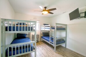 A room with bunk beds, a ceiling fan, and a small table. - Family Oasis w/ Private Pool in Cape Coral! (Cape Coral)