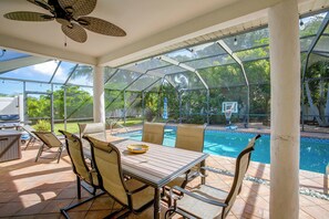 A covered outdoor area with a pool, chairs, and a table. - Family Oasis w/ Private Pool in Cape Coral! (Cape Coral)