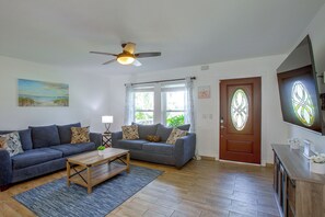 A living room with two sofas, a coffee table, a ceiling fan, and a door with a stained glass window. - Family Oasis w/ Private Pool in Cape Coral! (Cape Coral)