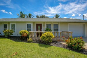Ein eingeschossiges Haus mit Veranda, Garage und gepflegtem Rasen.