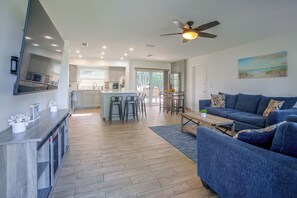 A modern kitchen with a central island, a dining area with chairs, a living room with a sofa and a coffee table, and a ceiling fan. - Family Oasis w/ Private Pool in Cape Coral! (Cape Coral)