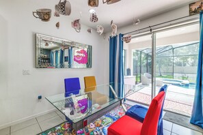 A modern living room with a glass coffee table, a large mirror, and a view of a swimming pool through a sliding glass door. - 8 Mi to Disney! Whimsical Home w/ Pool & Game Room (Kissimmee)