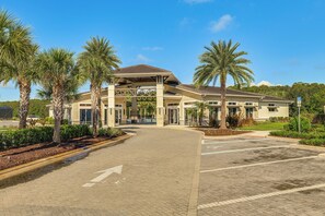 A hotel entrance with a covered walkway, palm trees, and a parking lot. - 8 Mi to Disney! Whimsical Home w/ Pool & Game Room (Kissimmee)