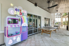 An outdoor seating area with a cotton candy machine, a ping pong table, and a covered patio. - 8 Mi to Disney! Whimsical Home w/ Pool & Game Room (Kissimmee)