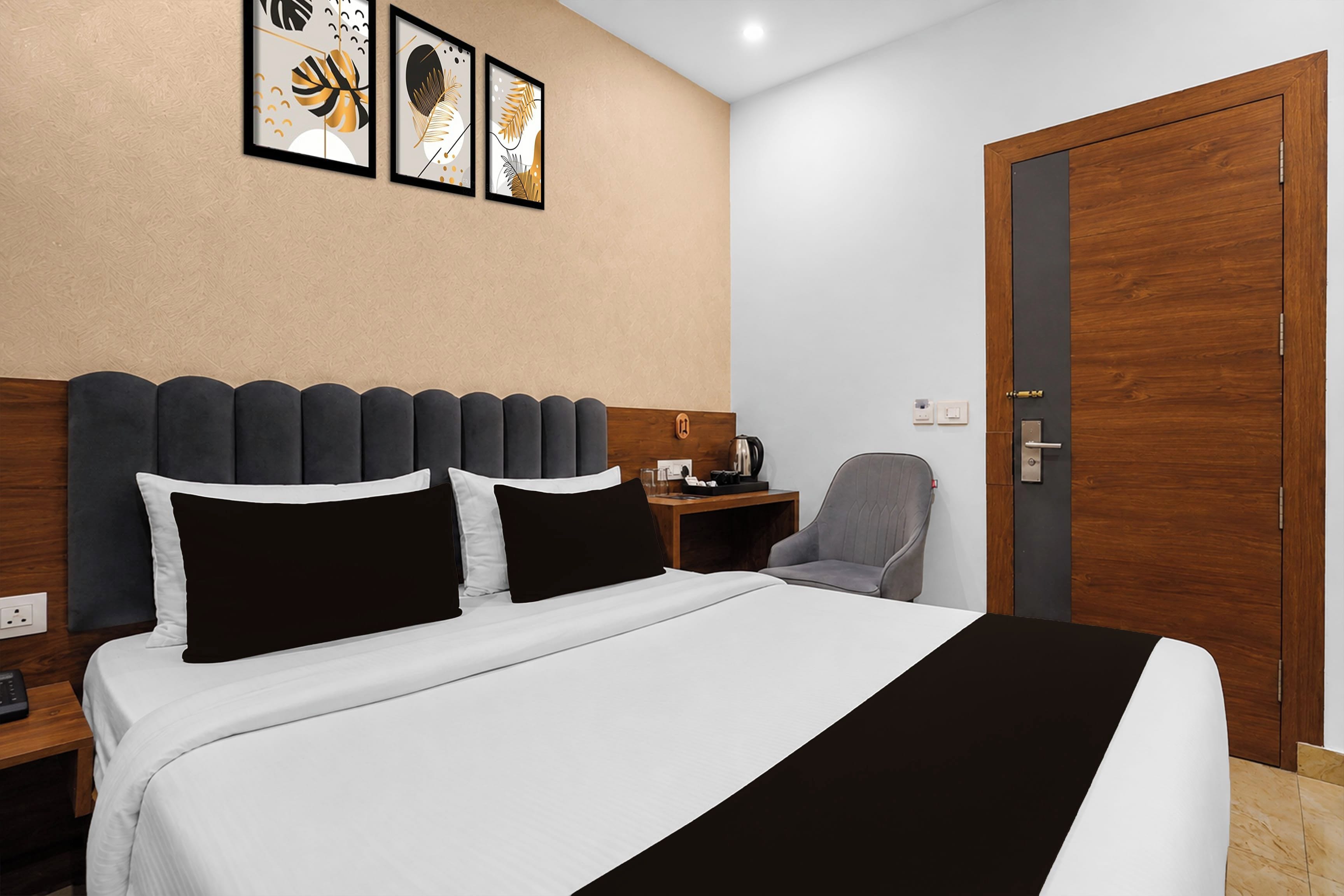 Habitación de hotel con cama, escritorio, silla, armario y cuadros en la pared.