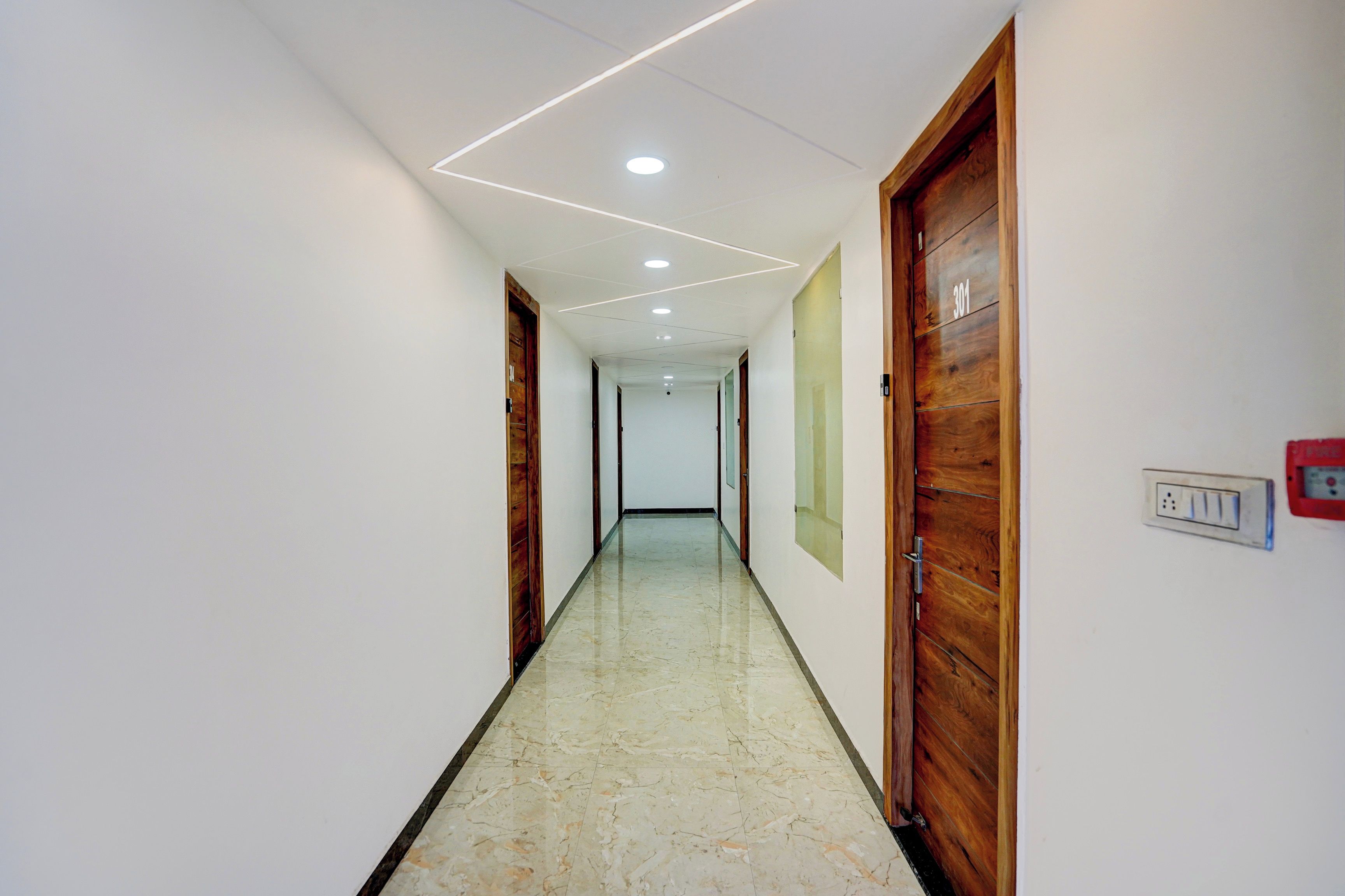 A hallway with wooden doors, a marble floor, and recessed ceiling lighting.