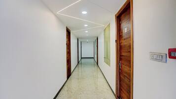 A hallway with wooden doors, a marble floor, and recessed ceiling lighting.