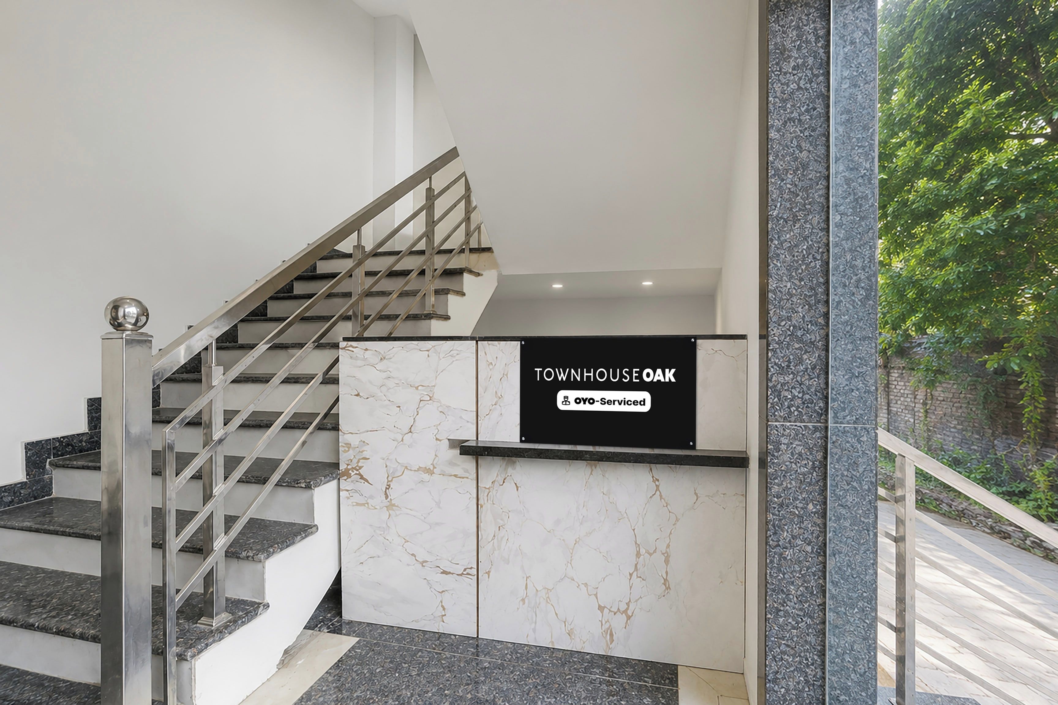 A staircase with a metal handrail and a sign indicating 'TOWNHOUSE OAK' with a logo for 'OYO-Serviced'.