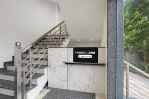 Una escalera con barandilla metálica y un cartel que indica 'TOWNHOUSE OAK' con el logotipo de 'OYO-Serviced'.