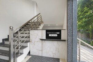 A staircase with a metal handrail and a sign indicating 'TOWNHOUSE OAK' with a logo for 'OYO-Serviced'.