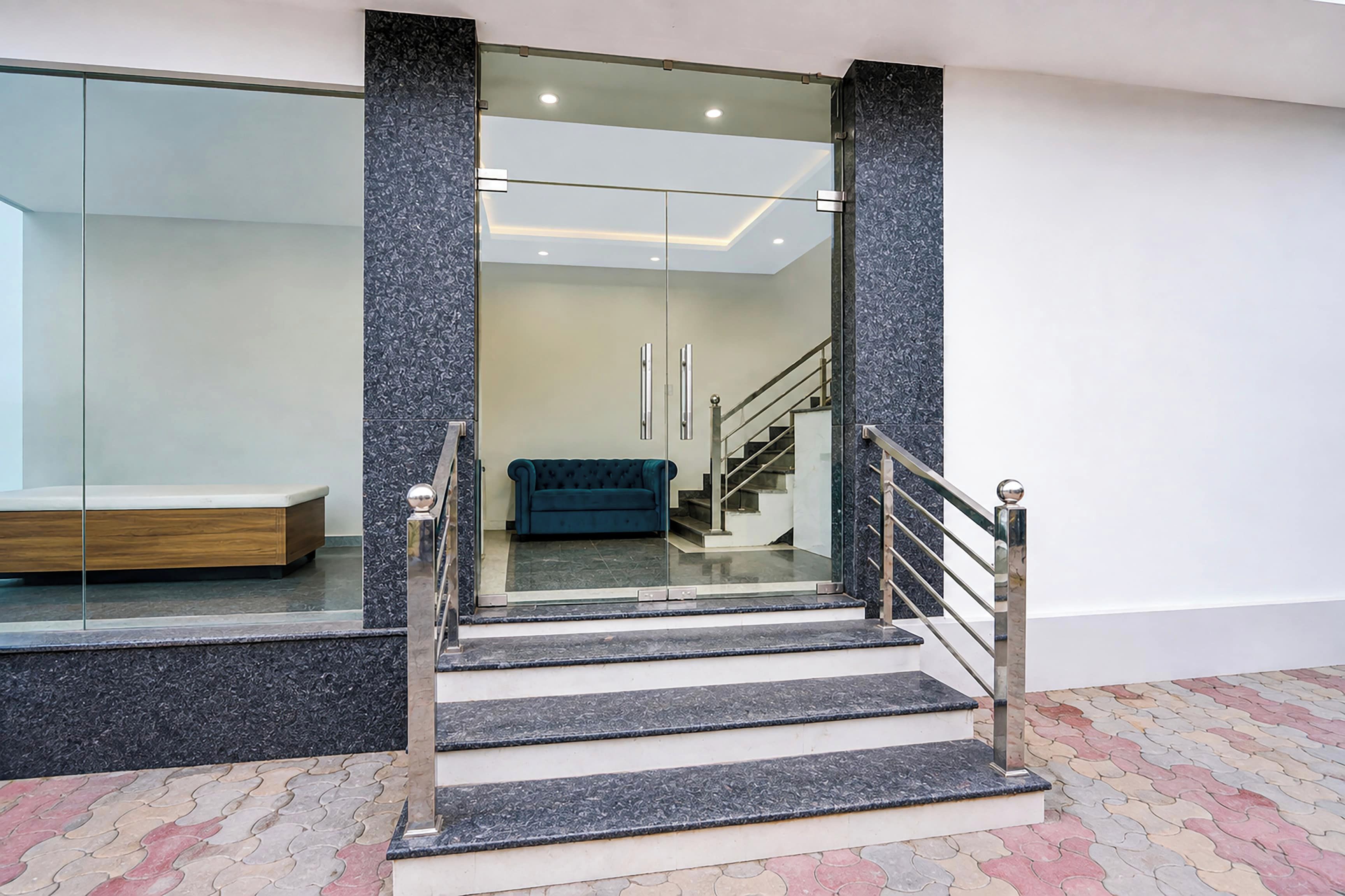 A modern staircase with glass doors leading to a room with a bench and a sofa.