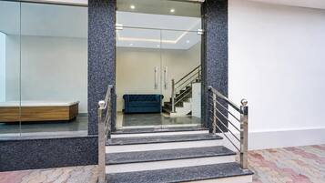 A modern staircase with glass doors leading to a room with a bench and a sofa.