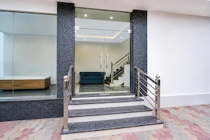 Una escalera moderna con puertas de vidrio que dan a un espacio con un banco y un sofá.