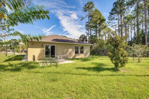 A single-story house with a patio, surrounded by a well-maintained lawn and trees. - 7 Mi to Beach! Group & Pet-friendly Palm Coast Gem (Palm Coast)
