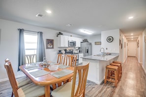 A modern kitchen with white cabinets, a stainless steel refrigerator, and a built-in microwave. - 7 Mi to Beach! Group & Pet-friendly Palm Coast Gem (Palm Coast)