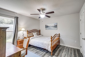 A bedroom with a bed, a chair, a desk, a ceiling fan, a painting, and a window with curtains. - 7 Mi to Beach! Group & Pet-friendly Palm Coast Gem (Palm Coast)