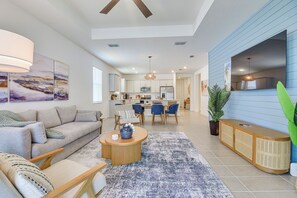 A modern living room with a sofa, coffee table, and a dining area with chairs and a kitchen in the background. - Private Community w/ Pool, Near Gulf Beaches (Palmetto)