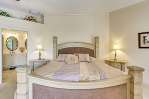 A well-appointed bedroom with a large bed, two bedside tables with lamps, a dresser, and a mirror. - Lanai w/ Pool & Spa! Rotonda West Retreat (Rotonda West)