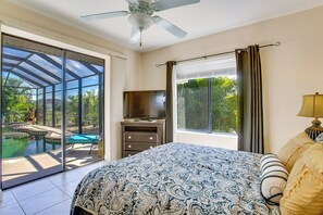A bedroom with a bed, a television, a window with curtains, and a ceiling fan. - Lanai w/ Pool & Spa! Rotonda West Retreat (Rotonda West)