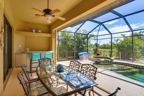 A glass-enclosed outdoor area with a pool, seating, and a ceiling fan. - Lanai w/ Pool & Spa! Rotonda West Retreat (Rotonda West)